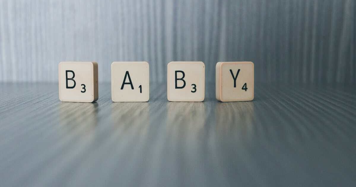 Scrabble-letters die het woord BABY vormen op een houten tafel
