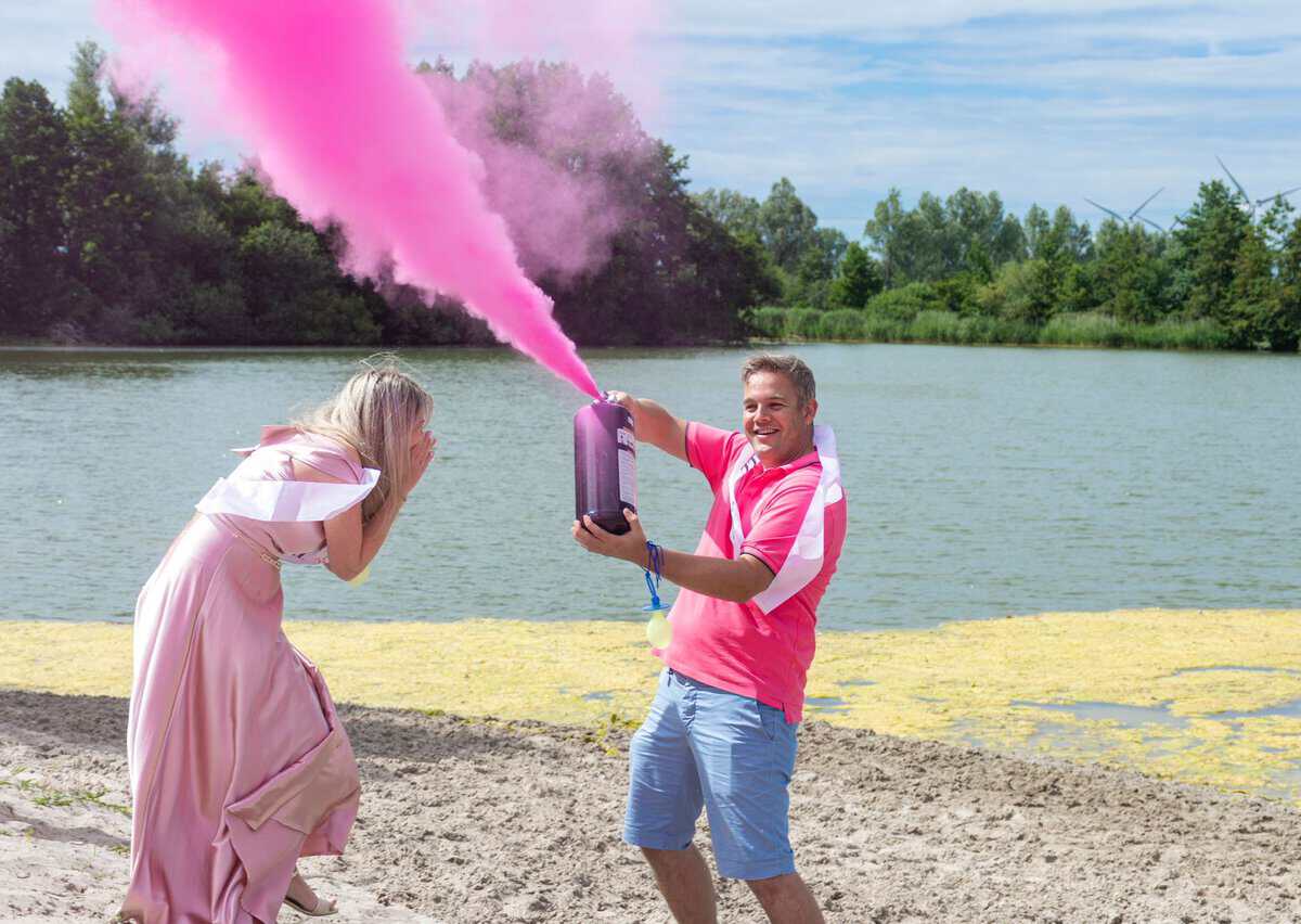 Grote gender reveal brandblusser van dichtbij terwijl hij een roze wolk de lucht in spuit