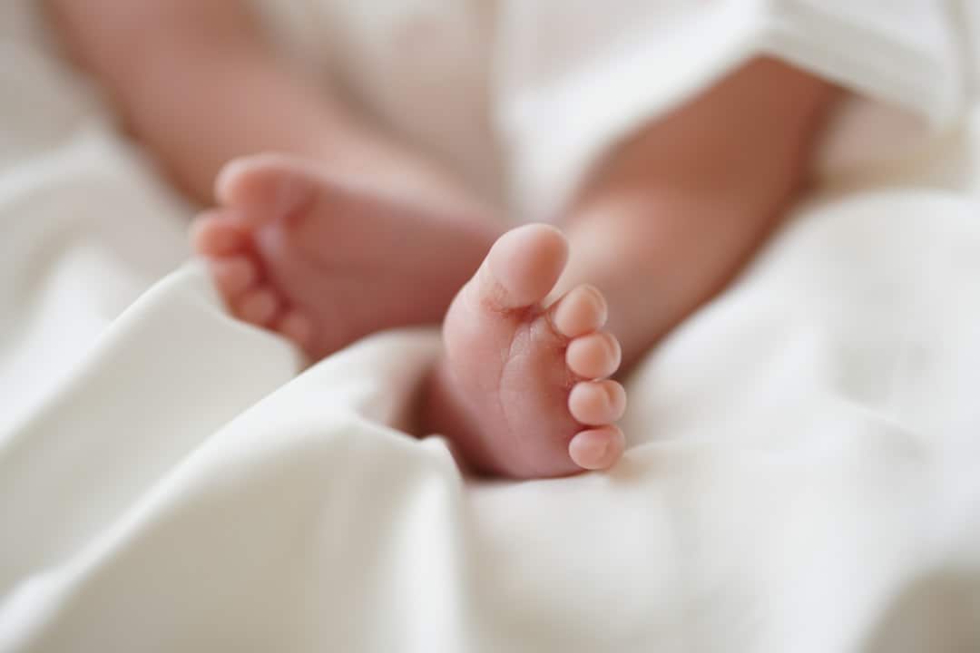 Kleine babyvoetjes op een zacht wit dekentje
